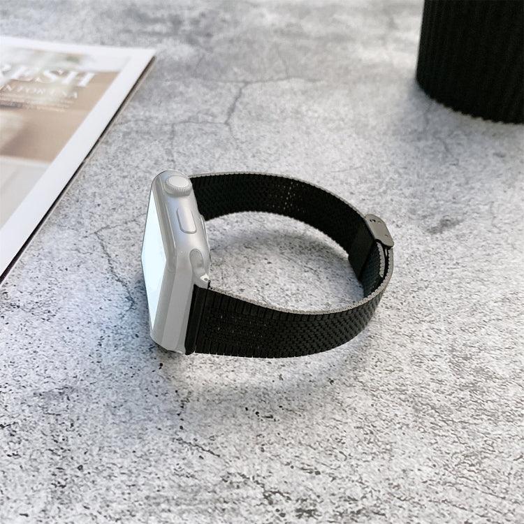 Buckle style steel replacement watchband for Apple Watch displayed on a gray surface with magazine and cup.