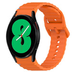 Wavy grain stitched silicone watch band for Samsung Galaxy Watch 4 in bright orange color.